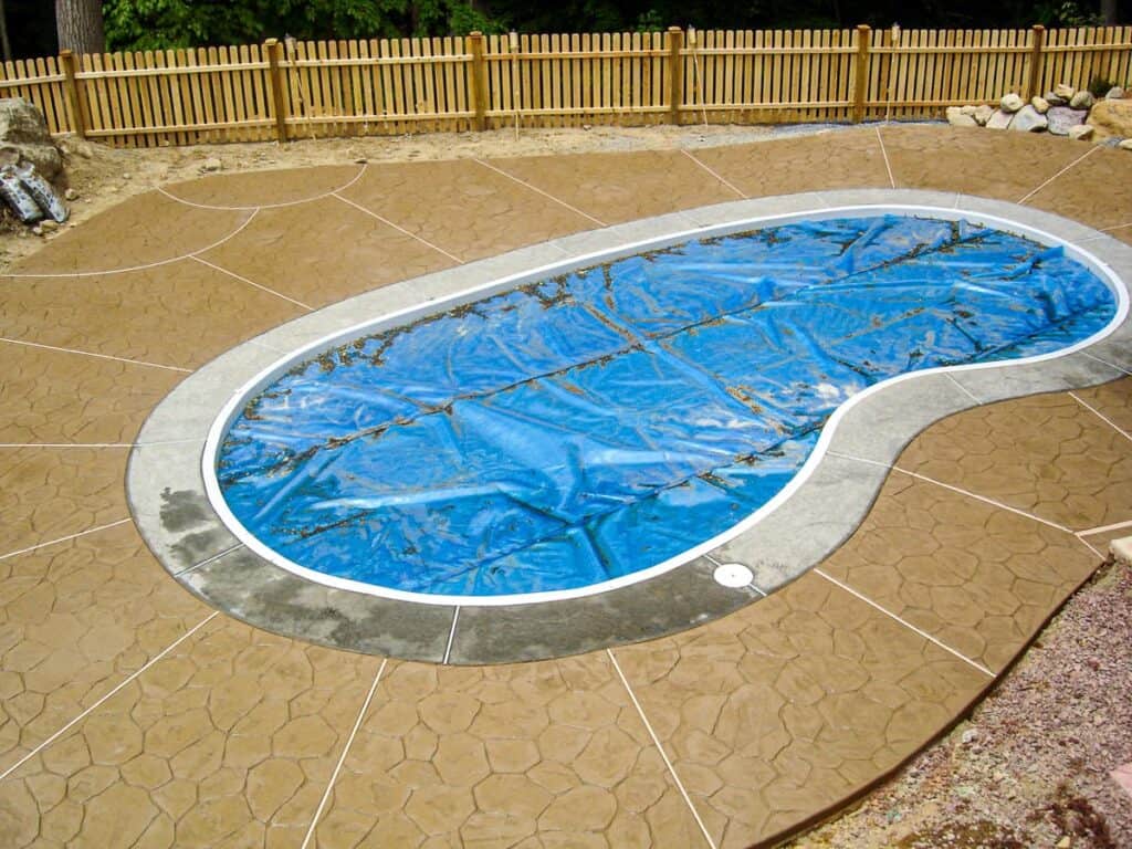 grey pool coping bordering an in-ground pool.