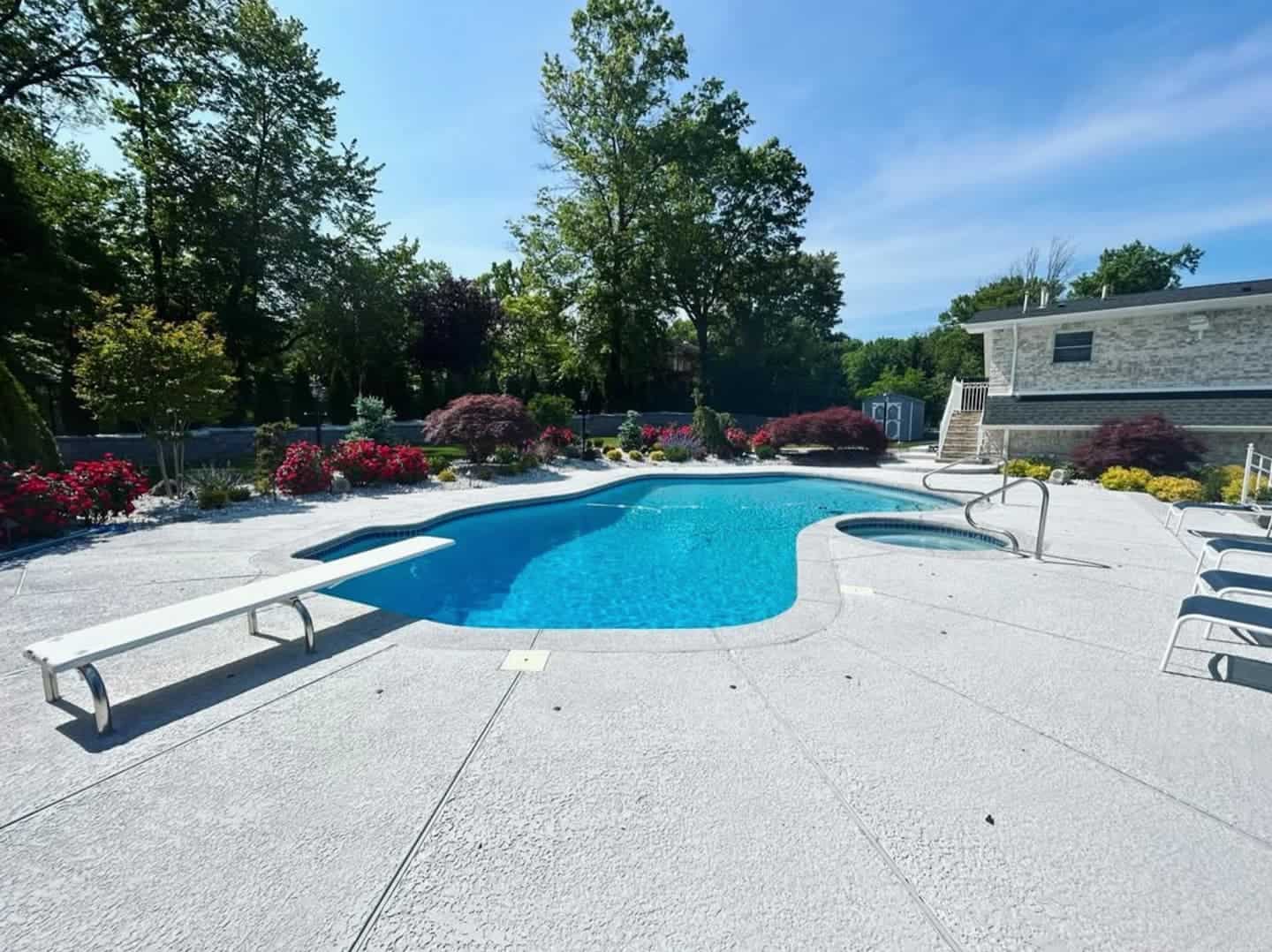 Grey frontier desert pool deck with plants, trees, and walls surrounding in the background.