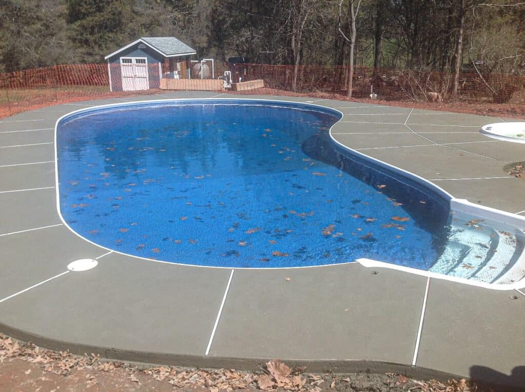 Tan plain concrete deck surrounding an in-ground pool and spa.